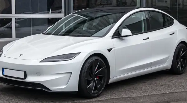 Tesla Model 3 blanco con techo negro. Su diseño aerodinámico sugiere una gran autonomía, optimizando la capacidad de la batería para viajes largos.