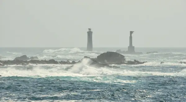 Deux phares se dressent sur des îlots rocheux battus par les vagues, au large de l'île d'Ouessant.