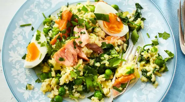 Reisgericht mit Lachs, Erbsen und Ei – ein Beispiel für gesund und lecker kochen. Frische Kräuter verfeinern die Mahlzeit.