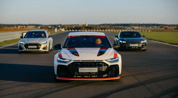 Trzy samochody Audi RS 8 na torze wyścigowym. Biały RS 8 z czerwonymi akcentami na pierwszym planie, za nim biały i czarny RS 8.