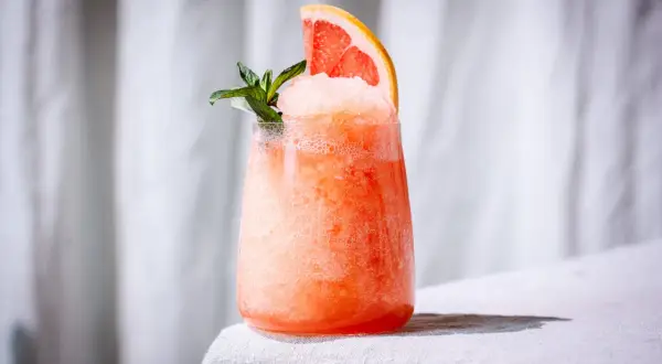 Erfrischender, gefrorener Aperol mit Grapefruitspalte und Minze. Perfekt für heiße Sommertage.