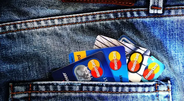 Kilka kart płatniczych, w tym Mastercard, w tylnej kieszeni dżinsów. Czy wiesz, preautoryzacja co to?