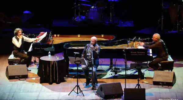 Sergio Cammariere e Enzo Sansone, mano nella mano, suonano i loro pianoforti in un concerto.