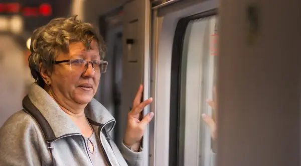 Starsza pani w okularach, podróżująca pociągiem, zastanawia się, ile znizki ma emeryt na PKP.