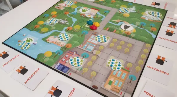 Kolorowa plansza do gry z motywem miasta i śladami łapek, idealna na gry planszowe dla 6 osób.