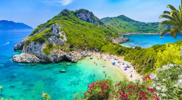 Grecja pogoda w kwietniu: malownicza zatoka z turkusową wodą, zielone wzgórza i plażowicze. Idealny czas na wypoczynek.