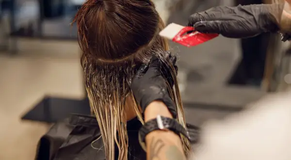 Friseur trägt Farbe auf, um einen sanften Farbverlauf zu erzielen. Die color melting Technik lässt die Töne harmonisch ineinander übergehen.