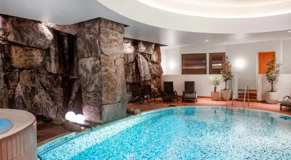 Avslappnande poolområde med stenformationer och bubbelpool, perfekt för en paus efter en dag som viking på ett hotell i Stockholm.