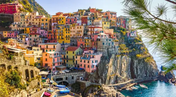 Färgstarka hus klättrar uppför klipporna vid havet i Italien. En vacker vy som ger fakta om Italien.