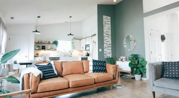 Nowoczesny salon z brązową kanapą i szarą sofą. Ciekawe łączenie kolorów ścian: dwa kolory ścian w jednym pokoju tworzą przytulną atmosferę.
