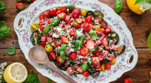En härlig somrig sallad med jordgubbar, vattenmelon, tomater och basilika på ett vackert fat.