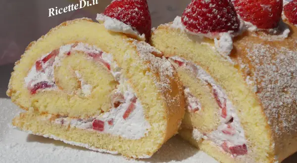 Un delizioso rotolo panna e fragole, soffice pan di Spagna arrotolato con crema e pezzetti di fragole fresche, decorato con zucchero a velo e fragole intere.