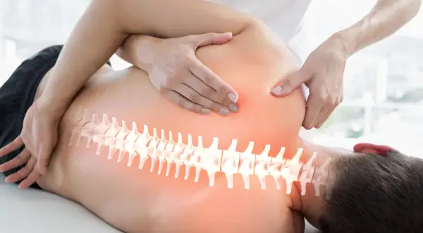 Hände eines Therapeuten behandeln den Rücken eines Mannes. Die Wirbelsäule ist hervorgehoben. Ein visueller Hinweis auf den Unterschied zwischen Osteopathie und Chiropraktiker.