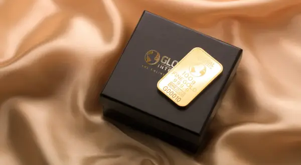Złoto dukatowe próba 999.9 na czarnym pudełku, prezentujące 100g sztabki z logo Global Intergold.