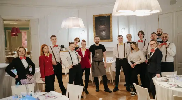 Zespół kelnerów w eleganckich strojach, z muszkami w stylu pellegrino, gotowy do obsługi przyjęcia.