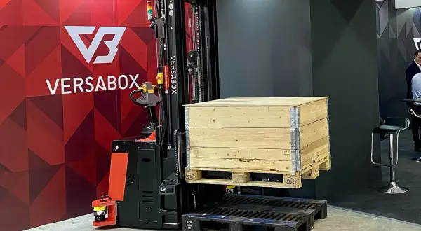 AGV robot VersaBox podnosi drewnianą skrzynię na palecie.