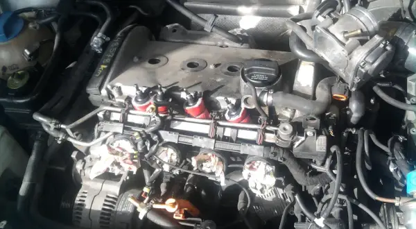 Silnik Audi A4 B6 2.0 benzyna w trakcie prac. Widoczne cewki zapłonowe, przepustnica i alternator.