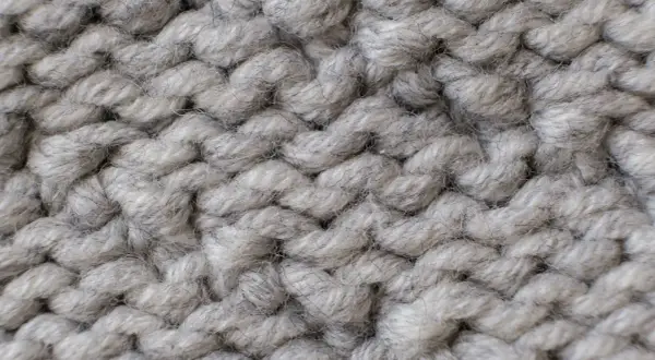 Nahaufnahme einer dicken, grauen Stricktextur. Die einzelnen Fäden sind flauschig und weich, ideal für das Mohair waschen.