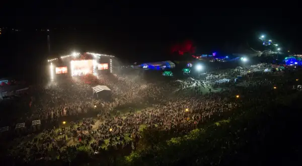 Tłum ludzi na koncercie festiwalu Audioriver, światła sceny i ekranów tworzą magiczną atmosferę nocnego wydarzenia.