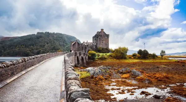 Kamienny most prowadzi do zamku Eilean Donan. Mglisty, jesienny klimat Szkocji podkreśla surowe piękno krajobrazu.