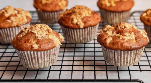 Mehrere goldbraune Haferflocken Muffins mit knuspriger Streusel-Decke auf einem Kuchengitter.