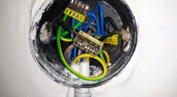 W puszce elektrycznej widać połączenia przewodów: niebieskich, zielono-żółtych i czarnych. Wygląda na to, że trwa zerowanie instalacji.