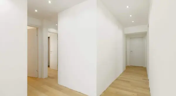 Corridoio moderno con pavimenti in legno e muretti divisori in cartongesso che creano un gioco di volumi.