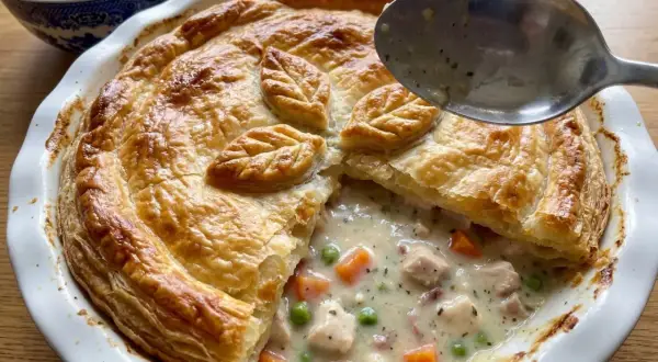 En gyllene kycklingpaj med krämig fyllning av kyckling, morötter och ärtor. Perfekt för ett mysigt kycklingpaj recept.