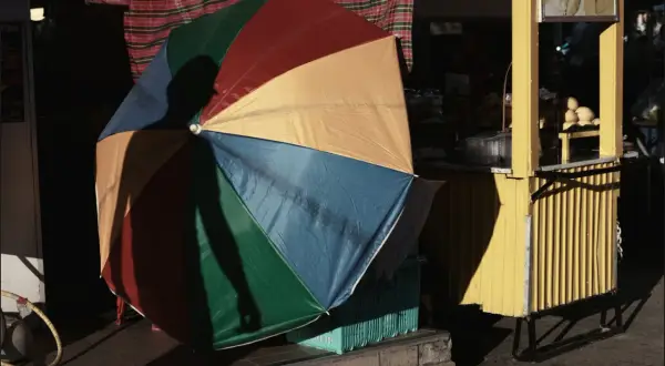 Kolorowy parasol rzuca cień na uliczny stragan z mango sticky rice. Tętniący życiem krajobraz miejski.