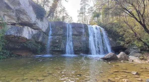 Cascada en la ruta 7 gorgs, con rocas cubiertas de musgo y vegetación, y un río de aguas claras.