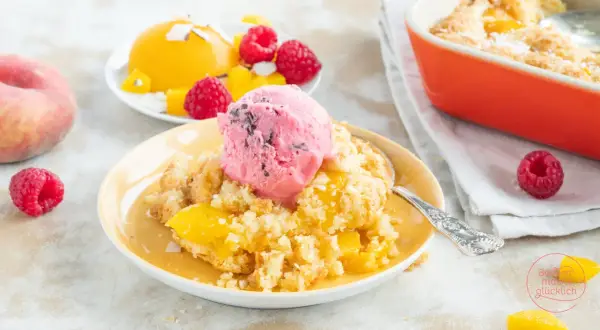 Ein warmer Pfirsich-Cobbler mit einer Kugel Himbeereis und frischen Himbeeren.