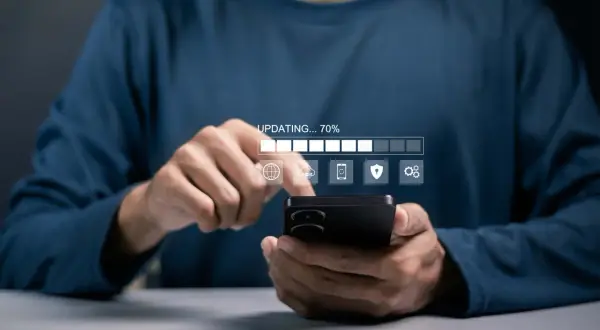 Osoba korzysta z telefonu, na którym widać pasek postępu "UPDATING... 70%" i ikony związane z aktualizacjami systemu Android.