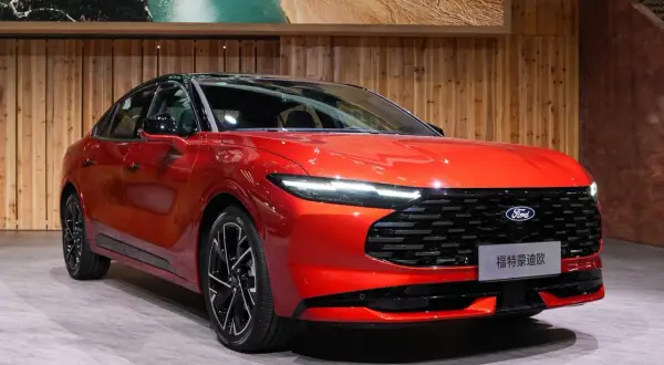 Nowy, lśniący, czerwony Ford Mondeo MK6 prezentuje się na tle drewnianej ściany i obrazu z krajobrazem.