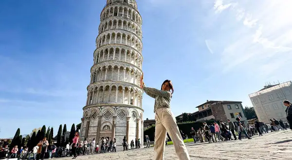 Ragazza fa finta di sorreggere la torre di Pisa, icona mondiale.