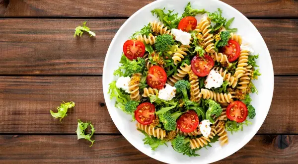 Kolorowa sałatka z makaronem fusilli, pomidorkami koktajlowymi, brokułami i fetą, polana musztardowym dressingiem. Pyszne danie na lekki obiad.