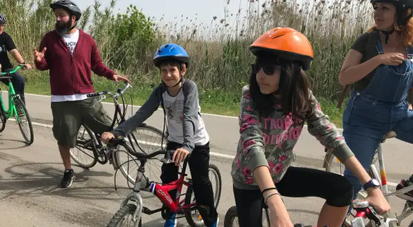 Familia disfrutando de rutas en bici con niños en Cataluña. Niños y adultos con cascos, listos para pedalear en un día soleado.