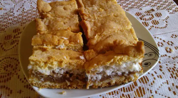 Pyszne ciasto z jabłkami i kokosem, pokrojone na kawałki, leży na talerzu.