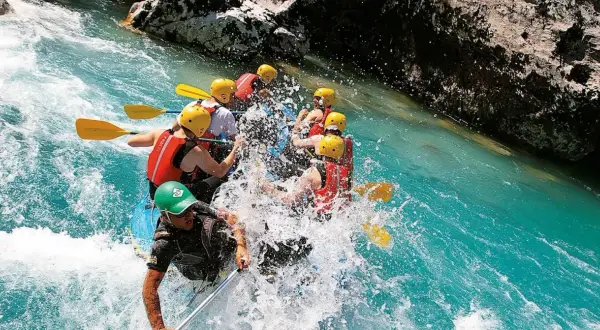 Un gruppo si diverte con il rafting nelle Marche, pagaiando tra spruzzi d'acqua cristallina e rocce imponenti. Un'avventura emozionante!