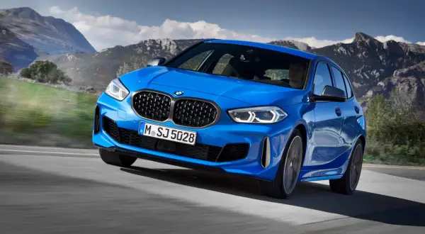 Niebieskie BMW Serii 1 F40 pędzi po górskiej drodze, kierowca skupiony na trasie.