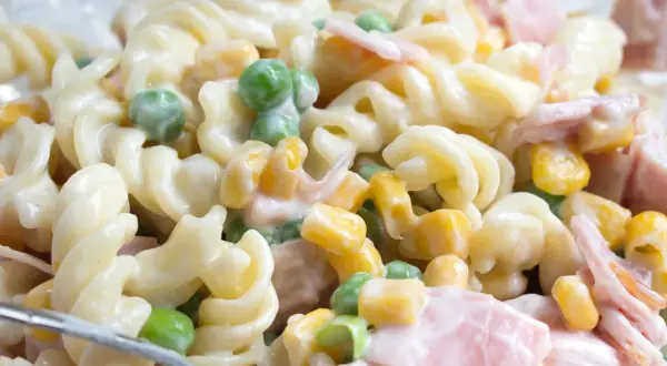 Ein einfacher Nudelsalat mit Spiralnudeln, Erbsen, Mais und Schinken in cremiger Soße.