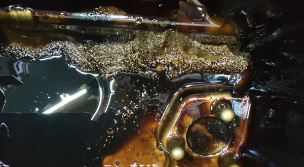 Metalowe opiłki w filtrze oleju silnikowego, świadczące o zużyciu elementów.