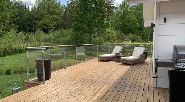 Ny slipad trall på altanen med solstolar och grill, redo för sommarens njutning i grönskan.