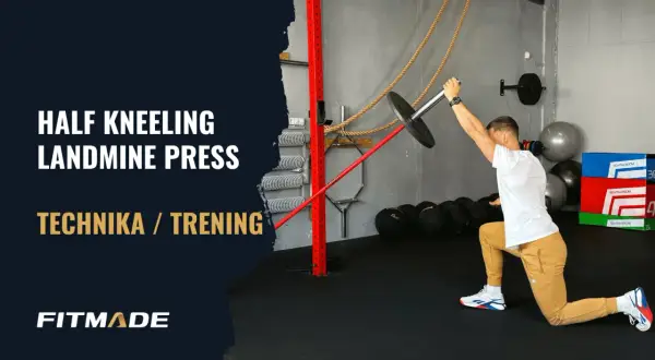 Mężczyzna w pozycji wykrocznej wykonuje ćwiczenie half kneeling landmine press.