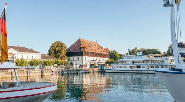 Boote am Bodensee, deutsche Flagge weht. Ein historisches Gebäude und ein Ausflugsschiff laden zu Konstanz Events ein.