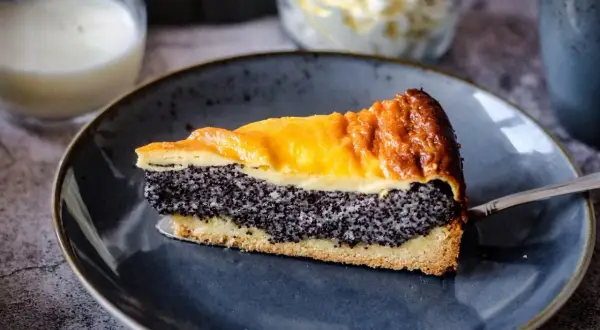 Ein Stück Mohn Schmand Kuchen mit goldbrauner Kruste und cremigem Mohn.