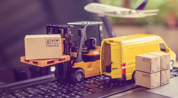 Miniatura wózka widłowego, żółtej furgonetki i samolotu na klawiaturze z pudełkami.