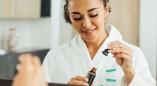 Frau im Bademantel nutzt ein Serum mit polyglutamic acid für strahlende Haut.