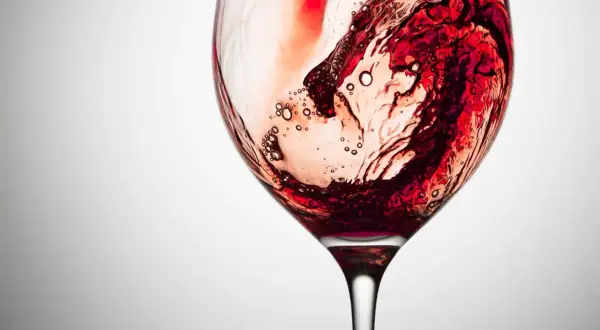 Vortice di vino rosso in un calice, con bollicine che rivelano la presenza dei tannini, responsabili della sensazione di astringenza.