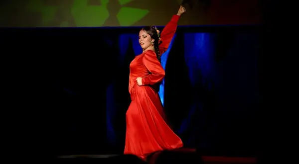 Una bailaora de flamenco, vestida de rojo pasión, evoca la fuerza y elegancia de los grupos de sevillanas.