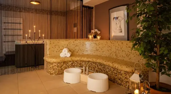 Relaks w spa: mozaikowa ławka, świece, wanna i rośliny tworzą atmosferę spokoju.